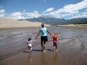 Mom and kids walking through the snow run off in the Sand Dunes National Park in Colorado